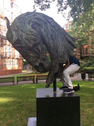 An image of someone putting their head into a horse's head statue for a team building activity