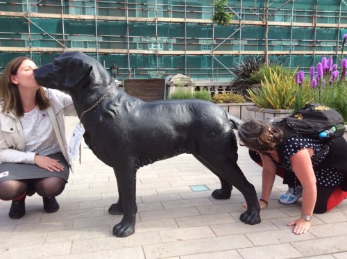 A picture of two people taking a picture with a dog statue